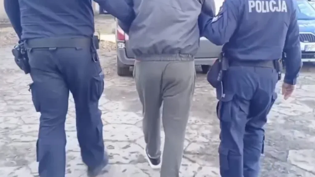 Policjanci prowadzą zatrzymanego mężczyznę w kajdankach